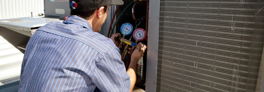 HVAC technician servicing a condenser unit in New Milford